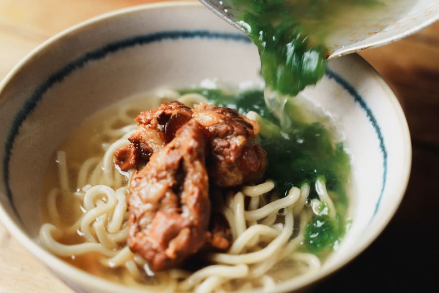 ソーキと自家製麺の入った丼に、出汁を注いでいく